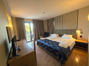 A hotel room with a bed, a desk with a chair, a small table, and a balcony with curtains. - Bora Bora (Nessebar)