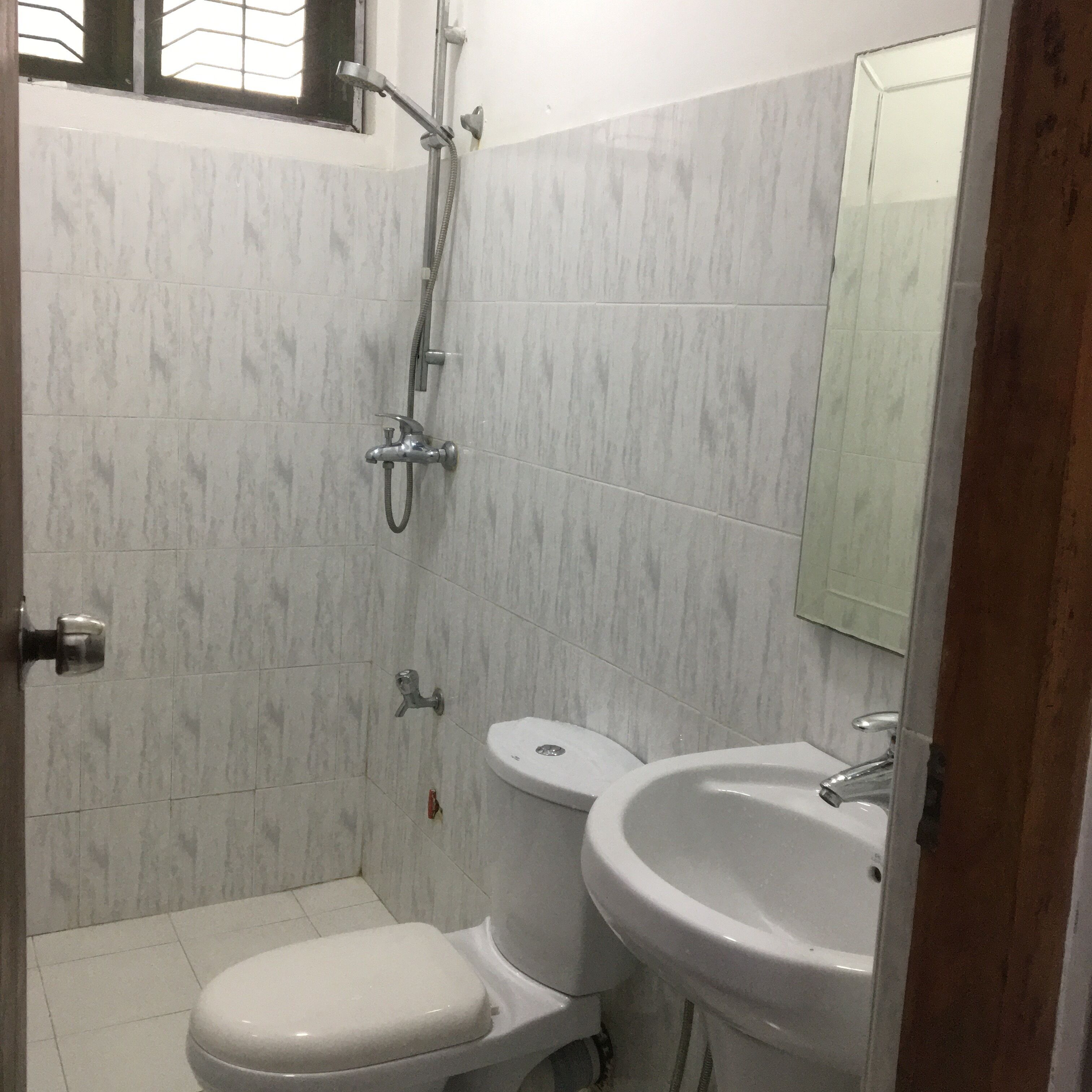 A small bathroom with a toilet, sink, and shower.