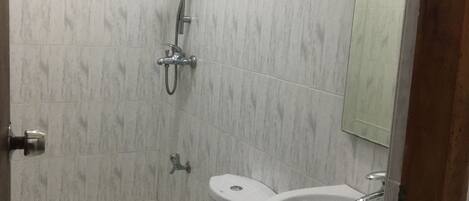 A small bathroom with a toilet, sink, and shower.