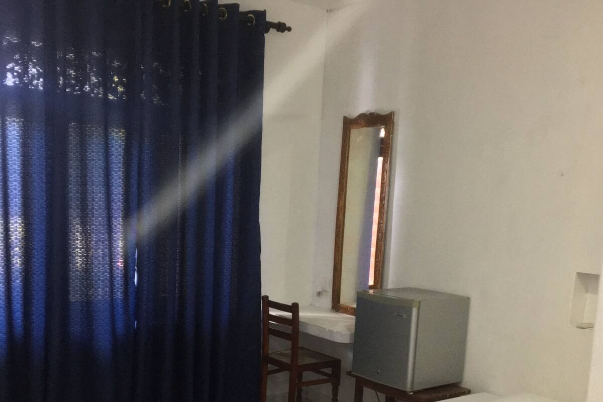 A bedroom with a bed, a desk, a chair, a mirror, and a television.