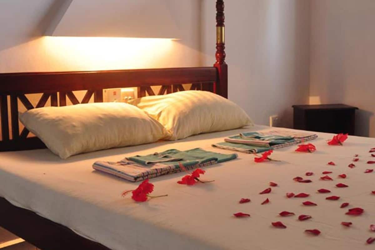 A neatly made bed with a white bedspread, two pillows, and a stack of magazines.
