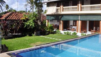 Guests can enjoy a balcony with windows and a door, overlooking a well-maintained lawn and pool.