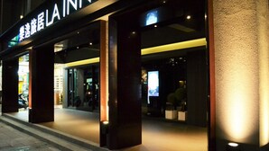 Esterno di un hotel con insegne illuminate e facciata moderna.