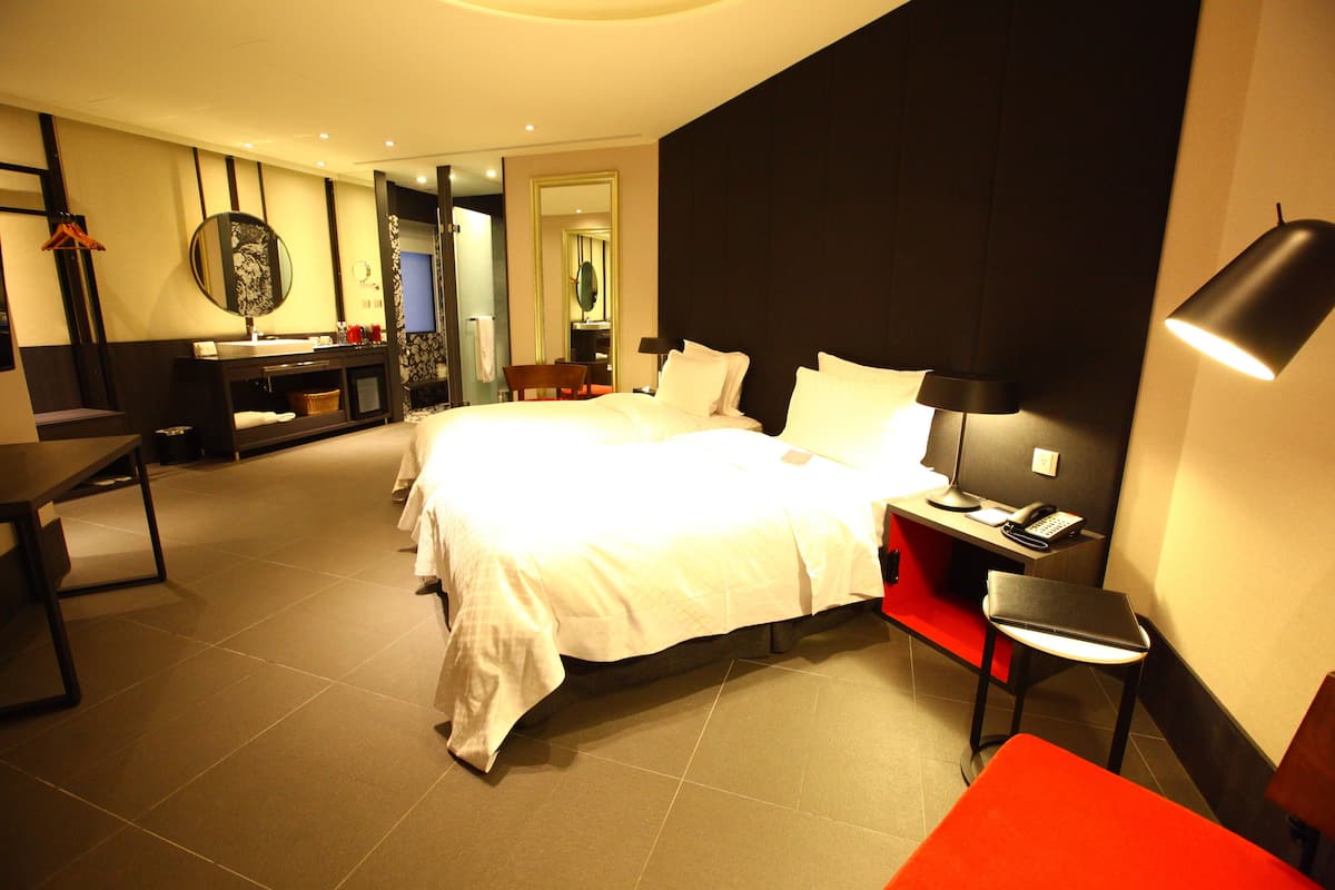 Ein Hotelzimmer mit einem großen Bett, einem Schreibtisch, einem Stuhl und einem kleinen Tisch.