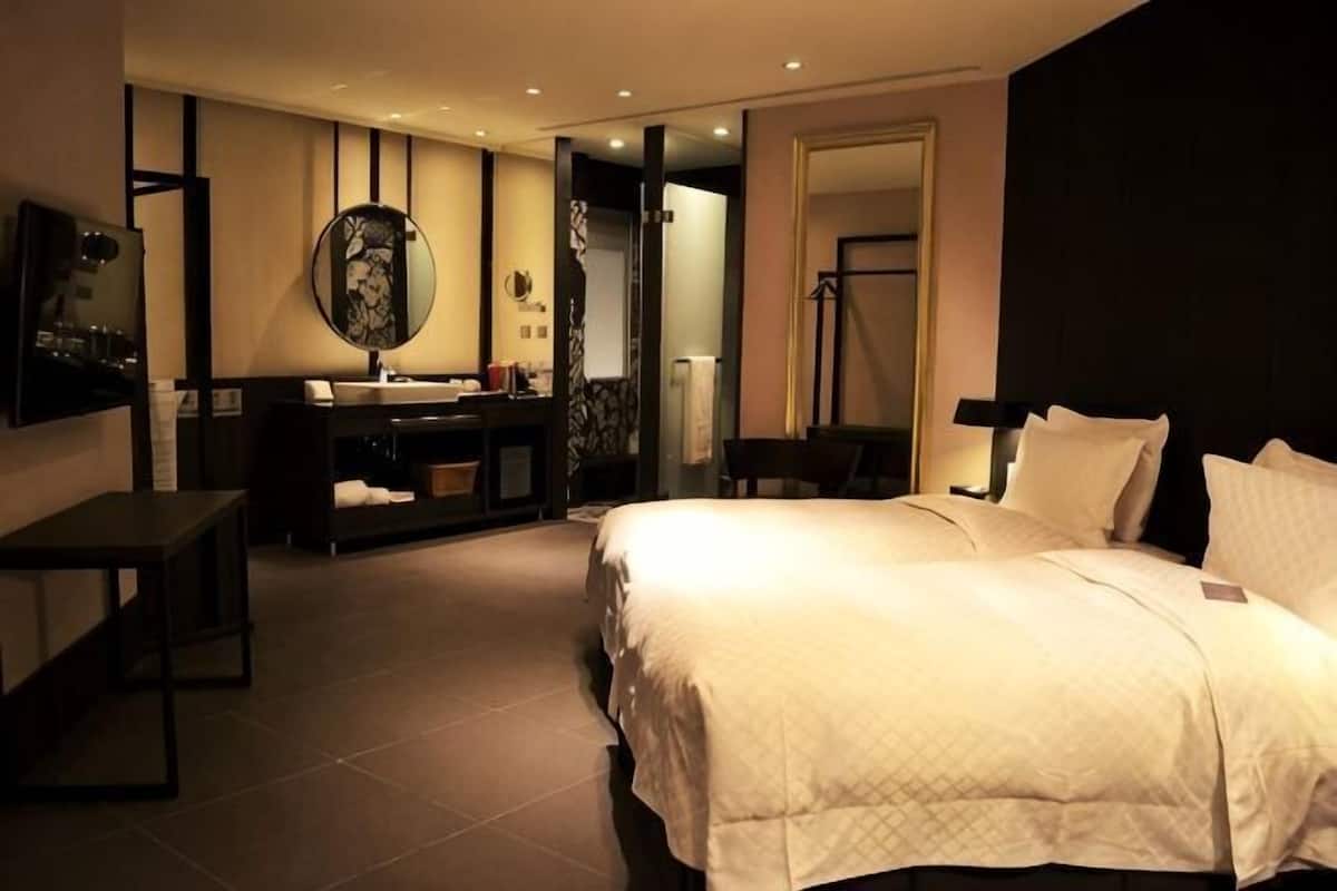 Ein Hotelzimmer mit Bett, Schreibtisch, Spiegel, Waschbecken und Kleiderschrank.