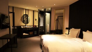 Una camera d'albergo con un letto, una toeletta con specchio, un lavandino e una porta che conduce a un'altra stanza.
