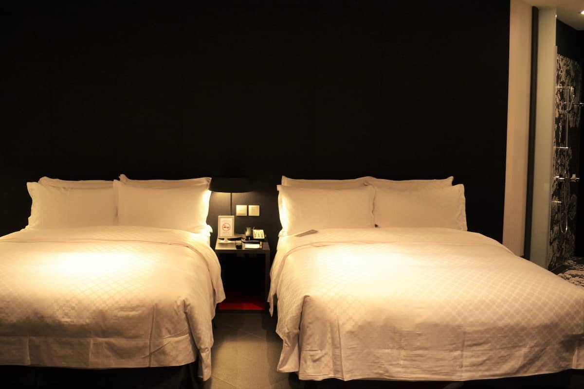 Ein Hotelzimmer mit zwei Betten, einem Nachttisch mit Lampe und einer Dusche.