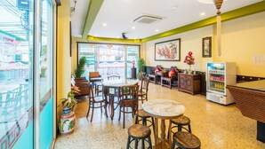 A restaurant with a glass wall, wooden furniture, and a vending machine.