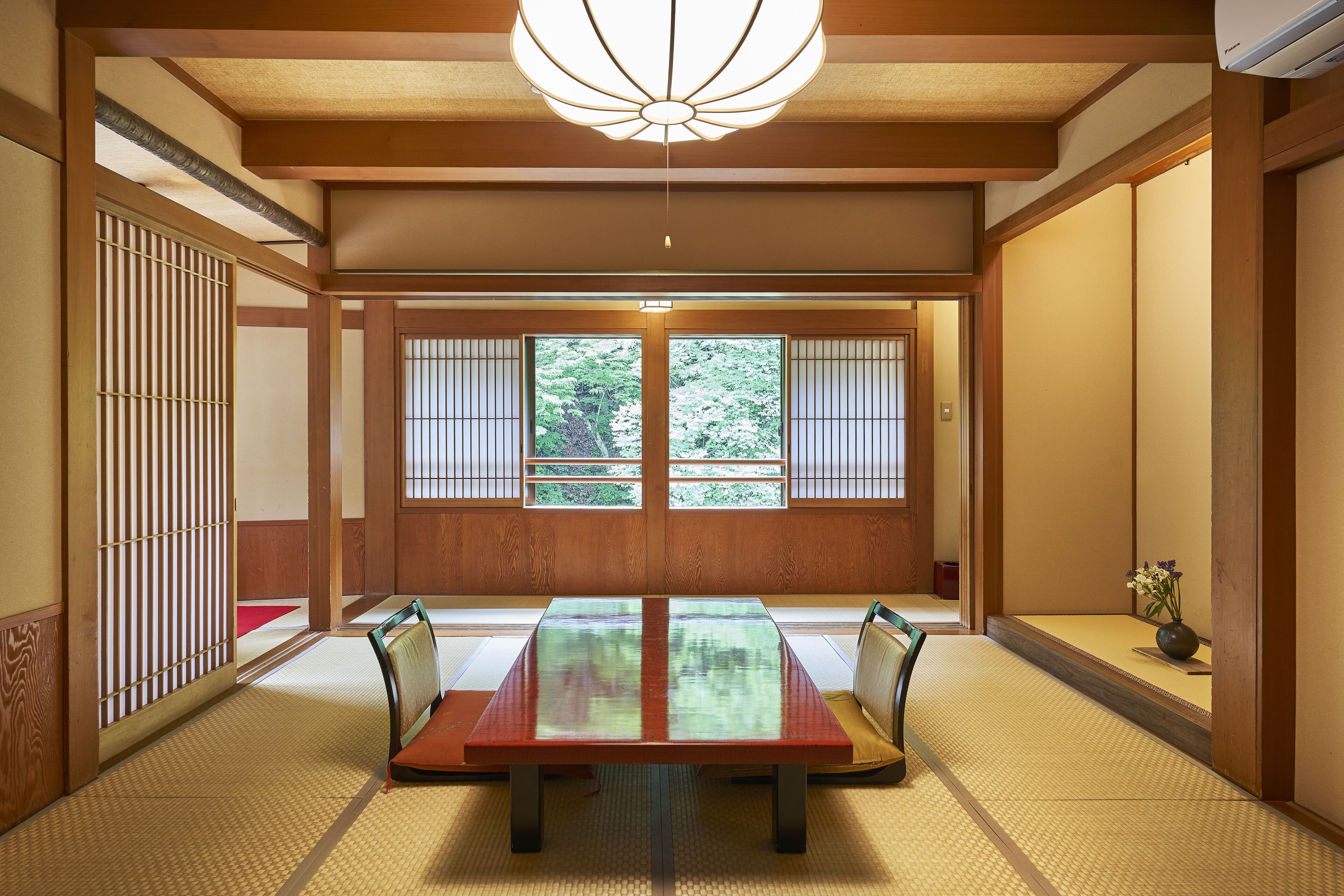 Una habitación japonesa tradicional con suelo de tatami, una mesa de madera baja y puertas correderas.