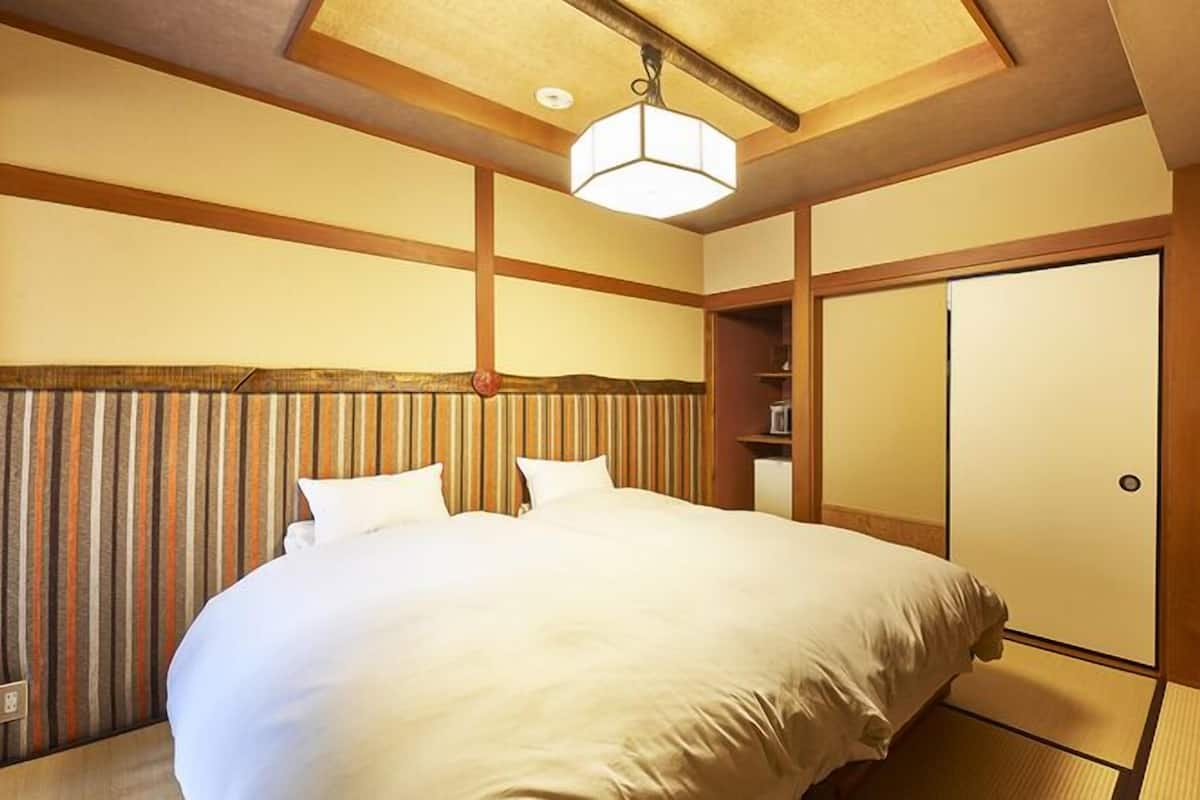 A hotel room with a large bed, wooden headboard, a wardrobe, and a ceiling light fixture.