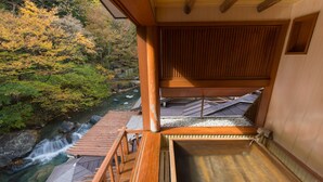 Eine Holzterrasse mit Blick auf einen Wasserfall und Herbstlaub.