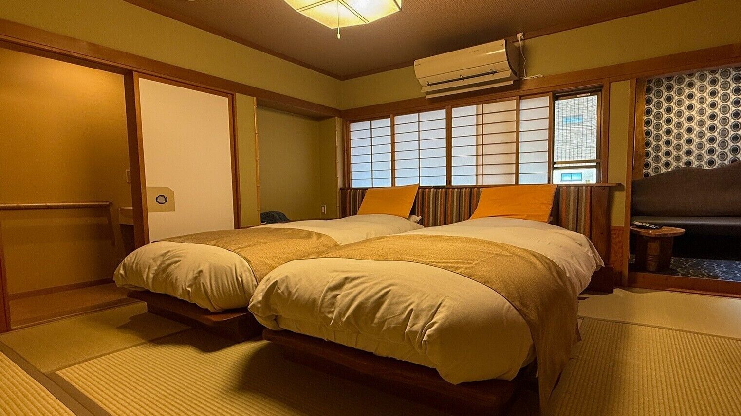 A traditional Japanese-style room with tatami flooring, a futon bed, sliding doors, and a shoji screen.