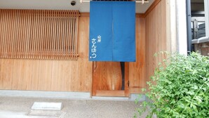 Un edificio japonés tradicional con fachada de madera y un letrero azul colgante.