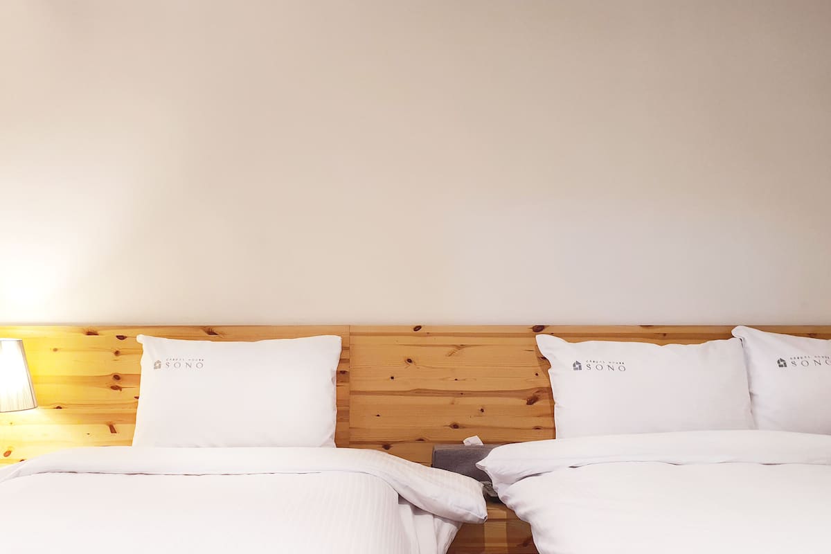Ein Hotelzimmer mit zwei Betten, einem Holzkopfende und weißer Bettwäsche.