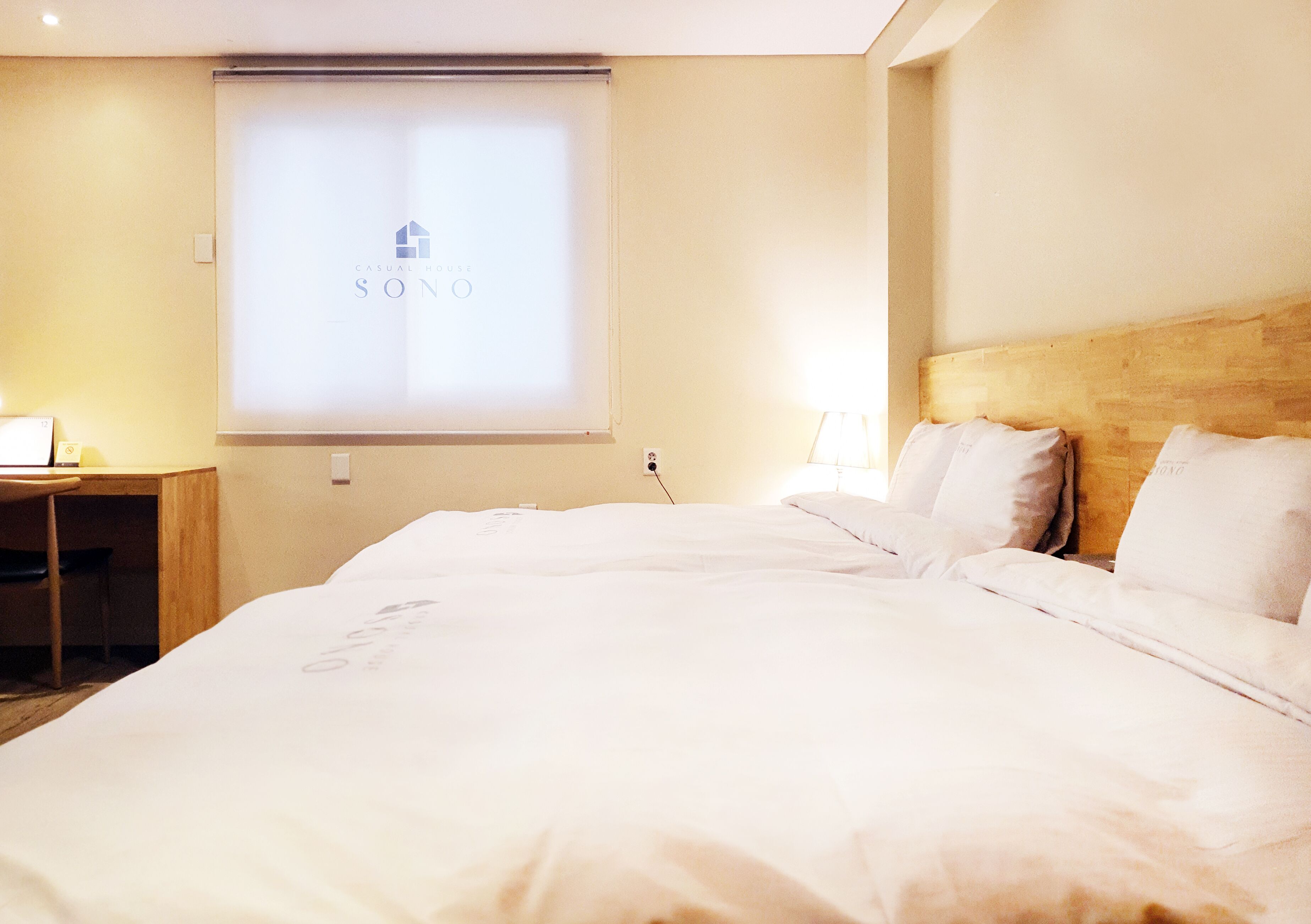 Ett hotellrum med en stor säng, ett skrivbord och en projektorduk som visar hotellets namn.