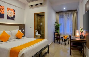 Habitación de hotel con cama, ducha, zona de comedor con mesa y sillas, y televisión.