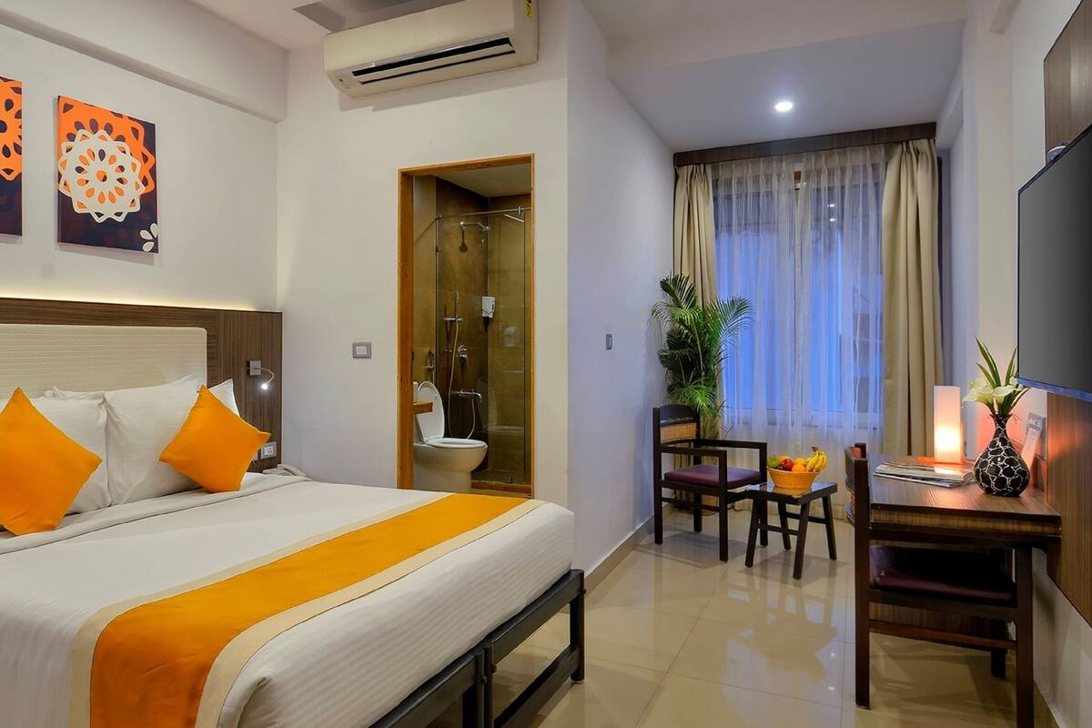 A hotel room with a bed, a shower, a dining area, and a TV.