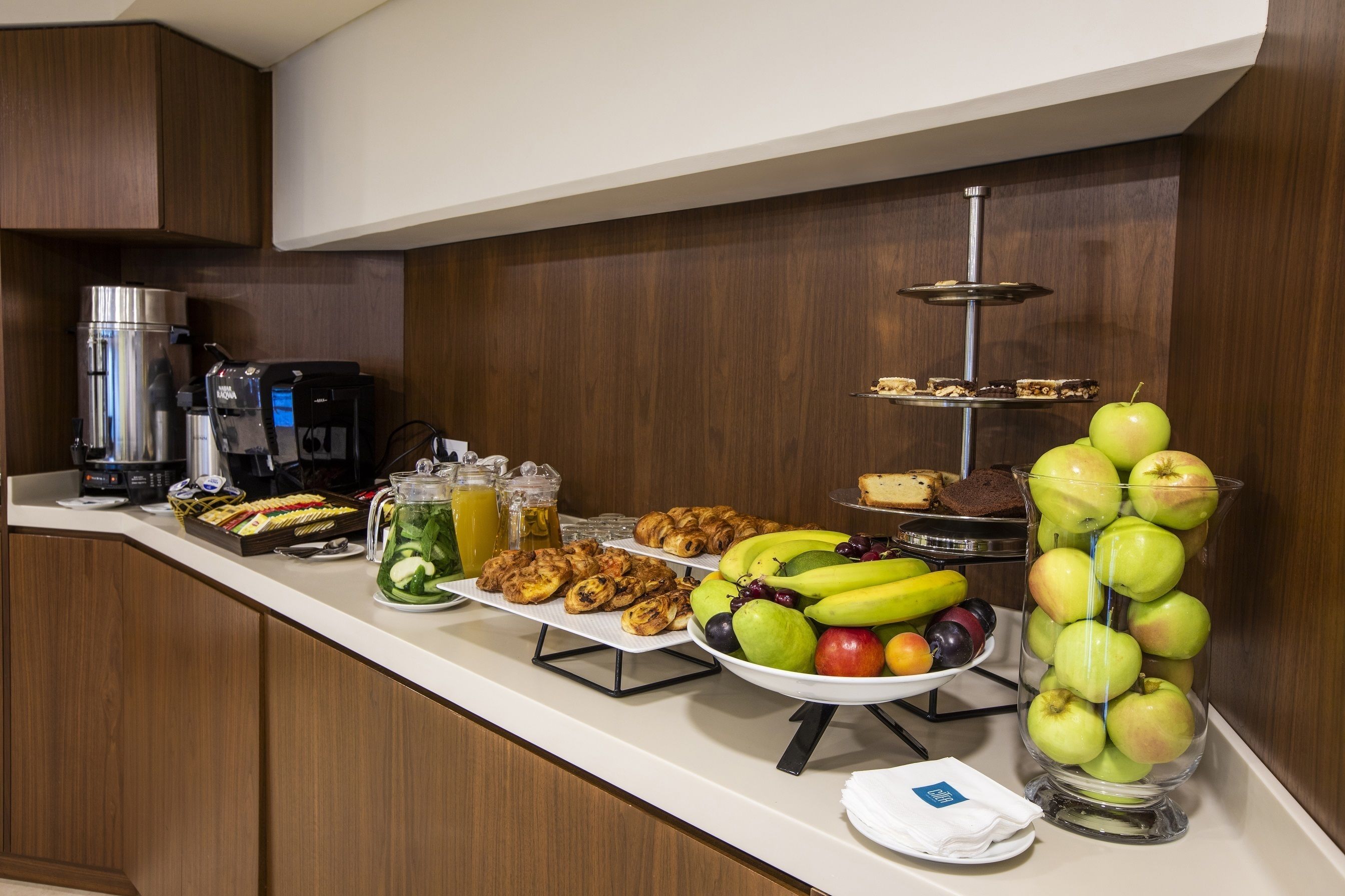 Un buffet de petit-déjeuner proposant une variété d’aliments, une machine à café et une présentation attrayante de fruits.