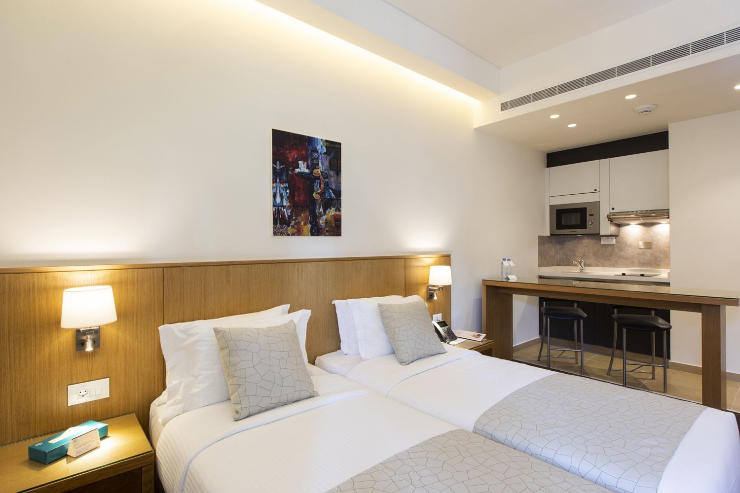 Una habitación de hotel con dos camas, un escritorio y una kitchenette.