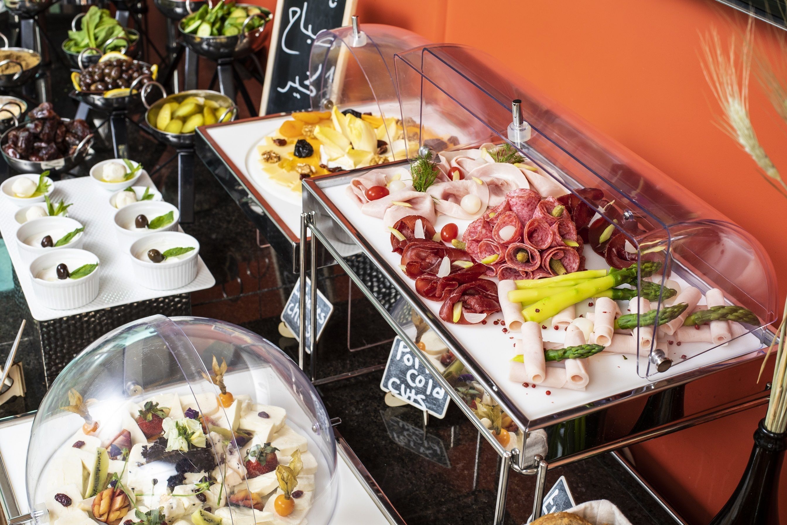 A buffet with various food items including meats, cheeses, and vegetables.