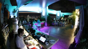 An outdoor dining area with tables and chairs, potted plants, and a city view at night. - Citea Apart-Hotel (Beirut)