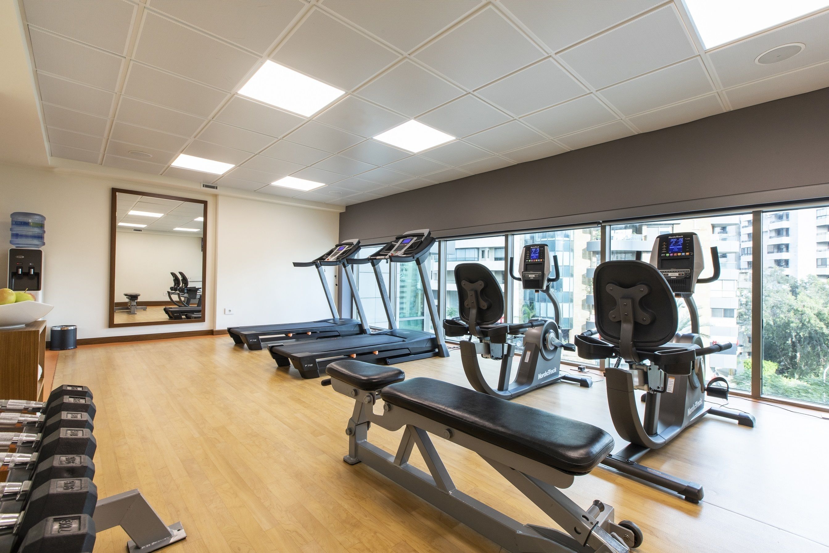 A gym with treadmills, weight machines, and dumbbells.