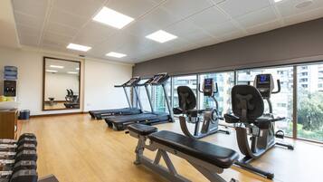 A gym with treadmills, weight machines, and dumbbells.