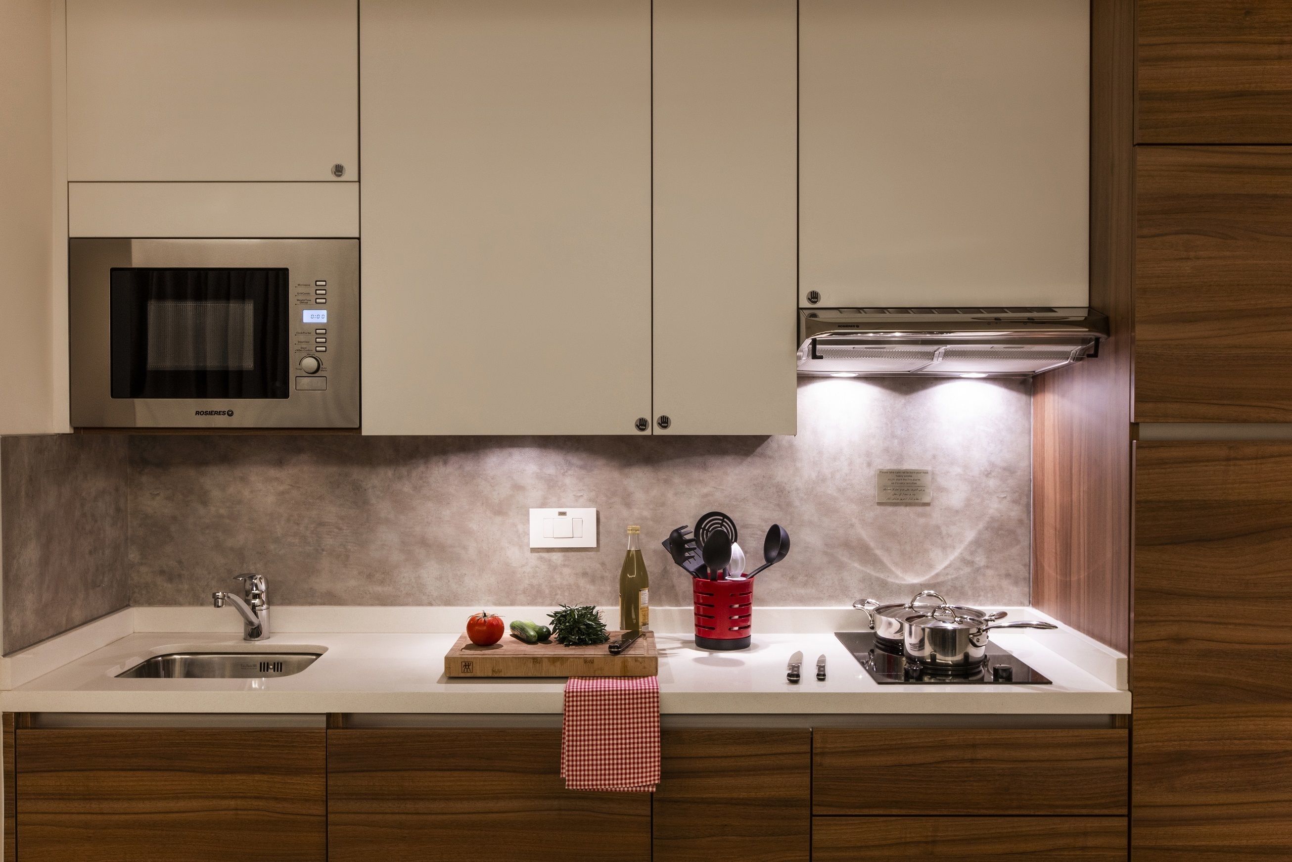 Una cocina moderna con microondas integrado, pileta de acero inoxidable y estufa a gas.