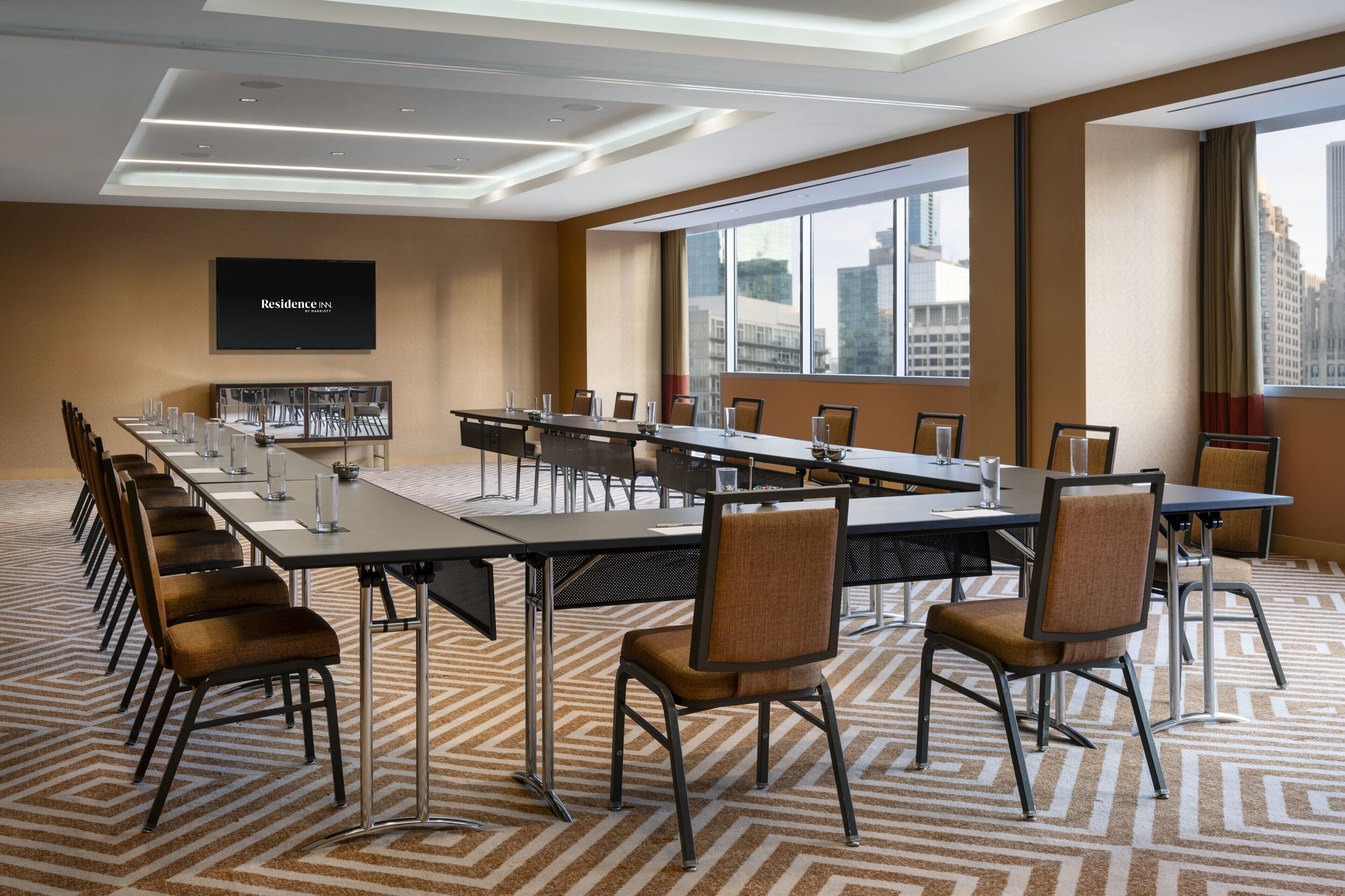 A conference room with a long table, chairs, and a television screen displaying "Residence Inn".