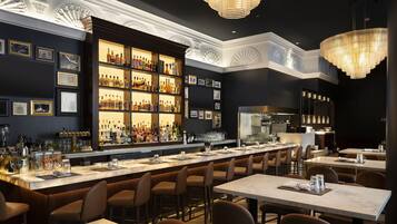 A bar area with a long counter, multiple seating options, and a well-stocked liquor display.