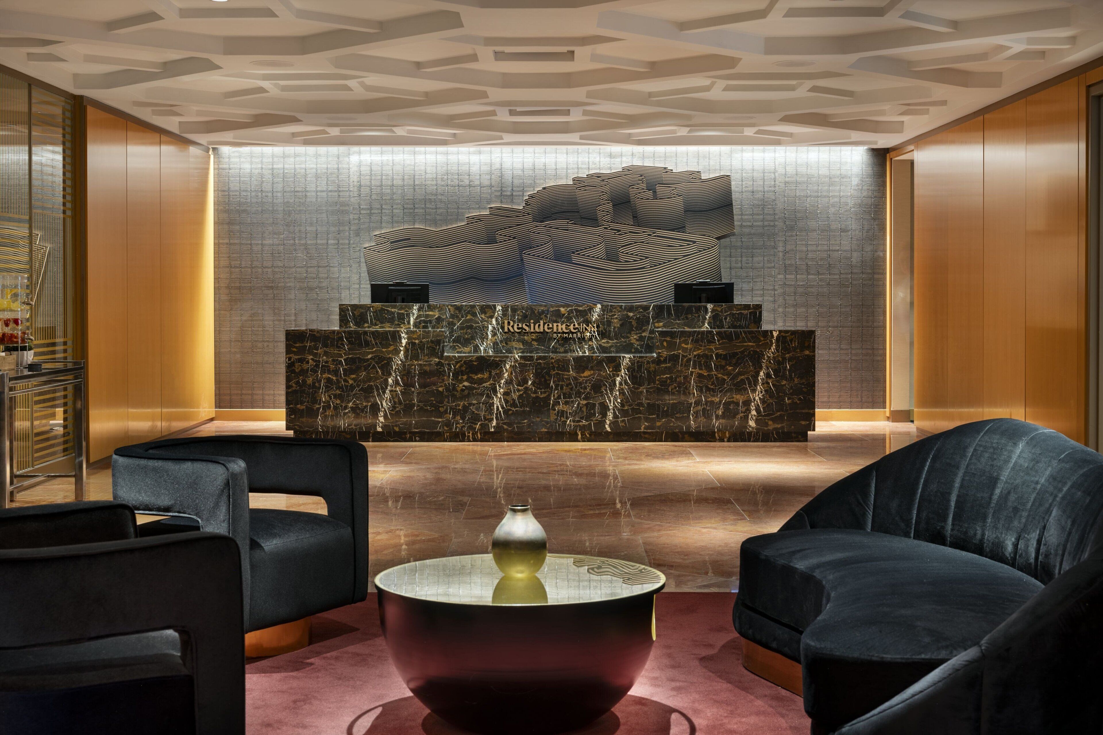 Una hall moderna con reception, zona salotto e parete decorativa.