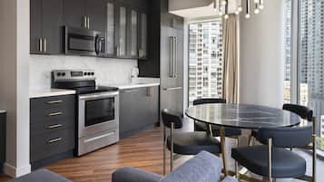A modern kitchen with dark cabinetry, stainless steel appliances, and a round dining table with chairs.