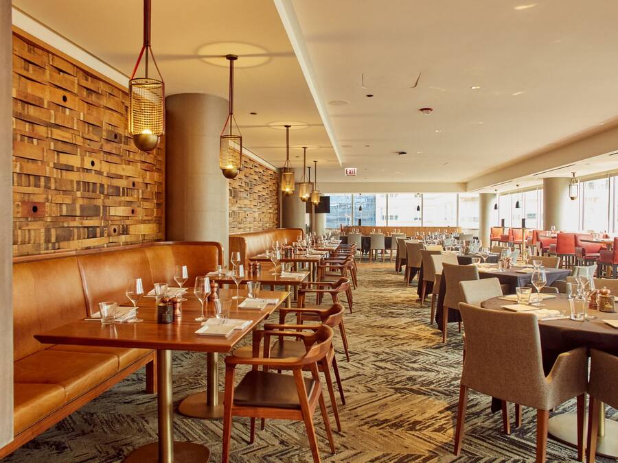 Un restaurant aux murs en bois, avec des banquettes en cuir et des tables dressées pour le service.