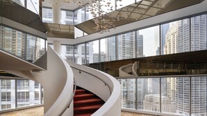 Un intérieur moderne avec un escalier en colimaçon, de grandes fenêtres et un sol orné de motifs géométriques.