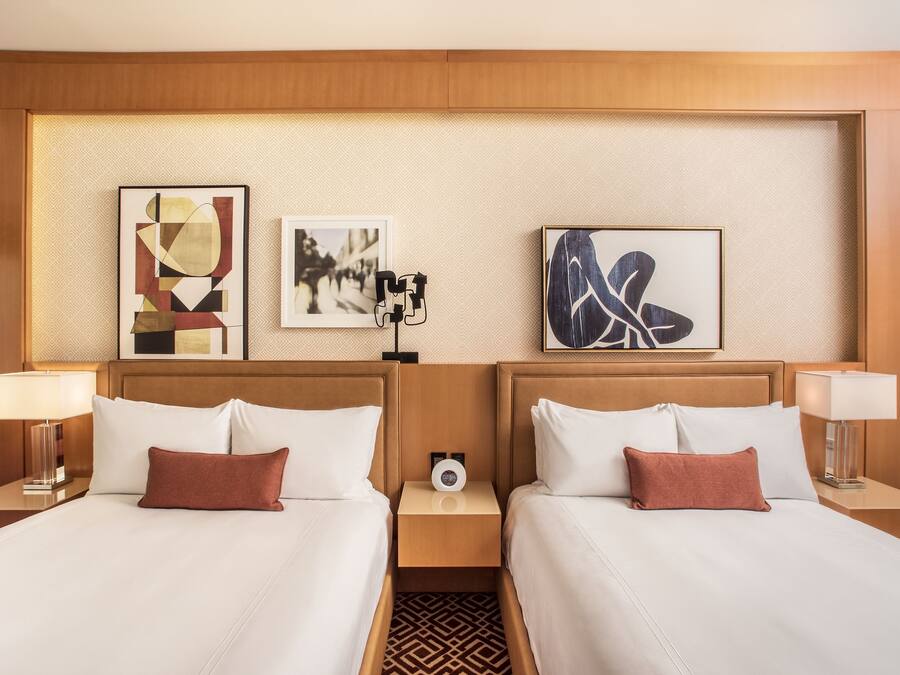 Habitación de hotel con dos camas, cabecero de madera y una obra de arte en la pared.