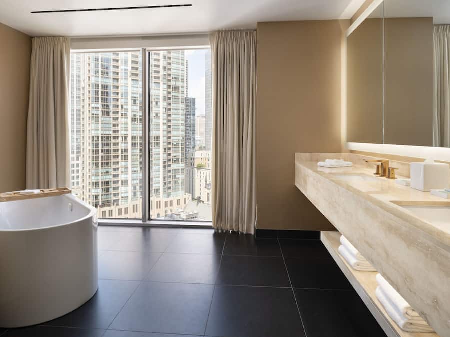 A modern bathroom with a large bathtub, a double sink vanity, and a large mirror.