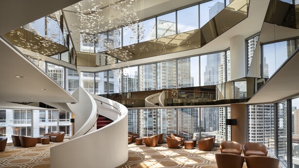 A modern hotel lobby with a spiral staircase, seating areas, and large windows offering city views. - Residence Inn Chicago Downtown Magnificent Mile (Chicago)