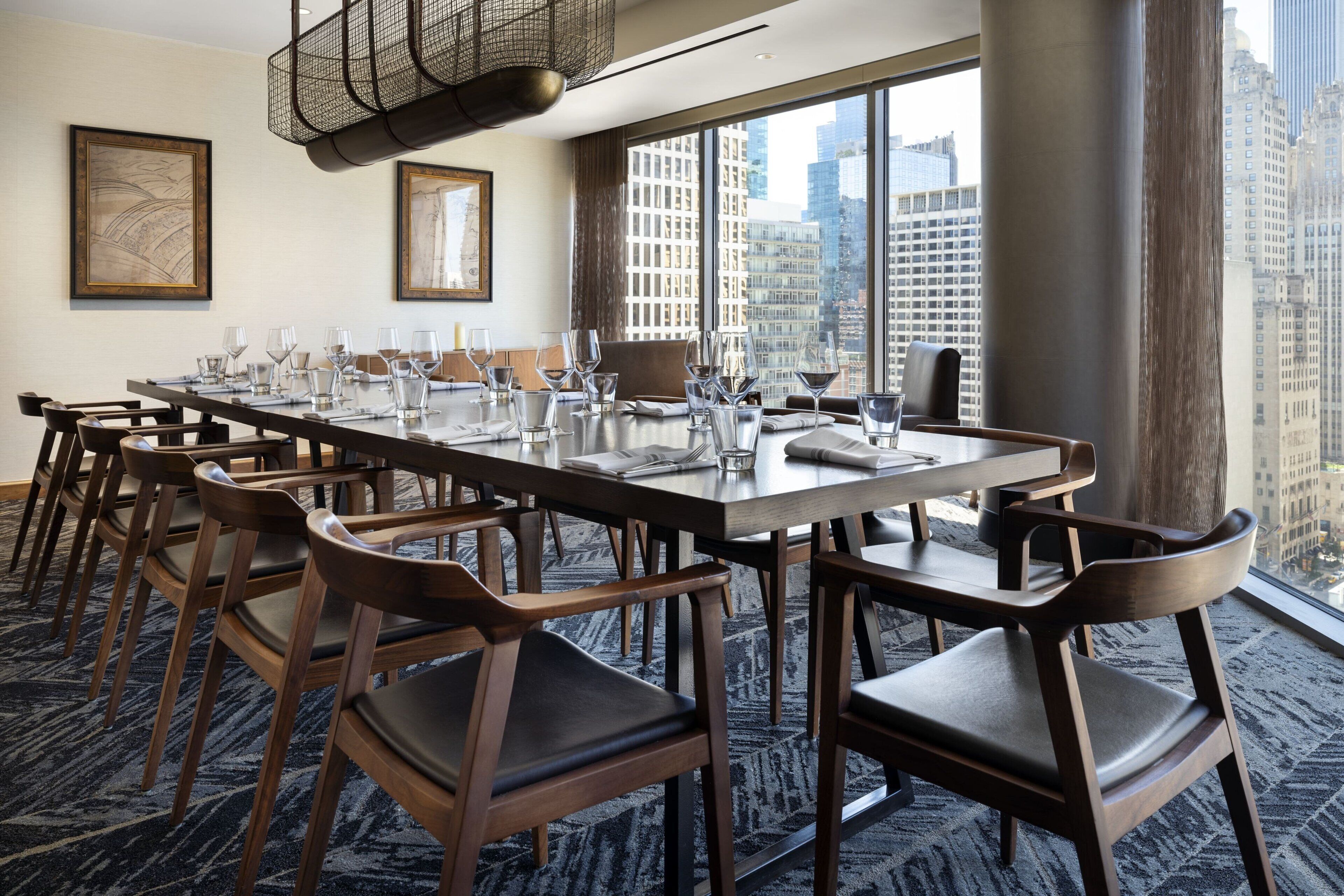 A conference room with a long table, multiple chairs, and large windows offering a city view.