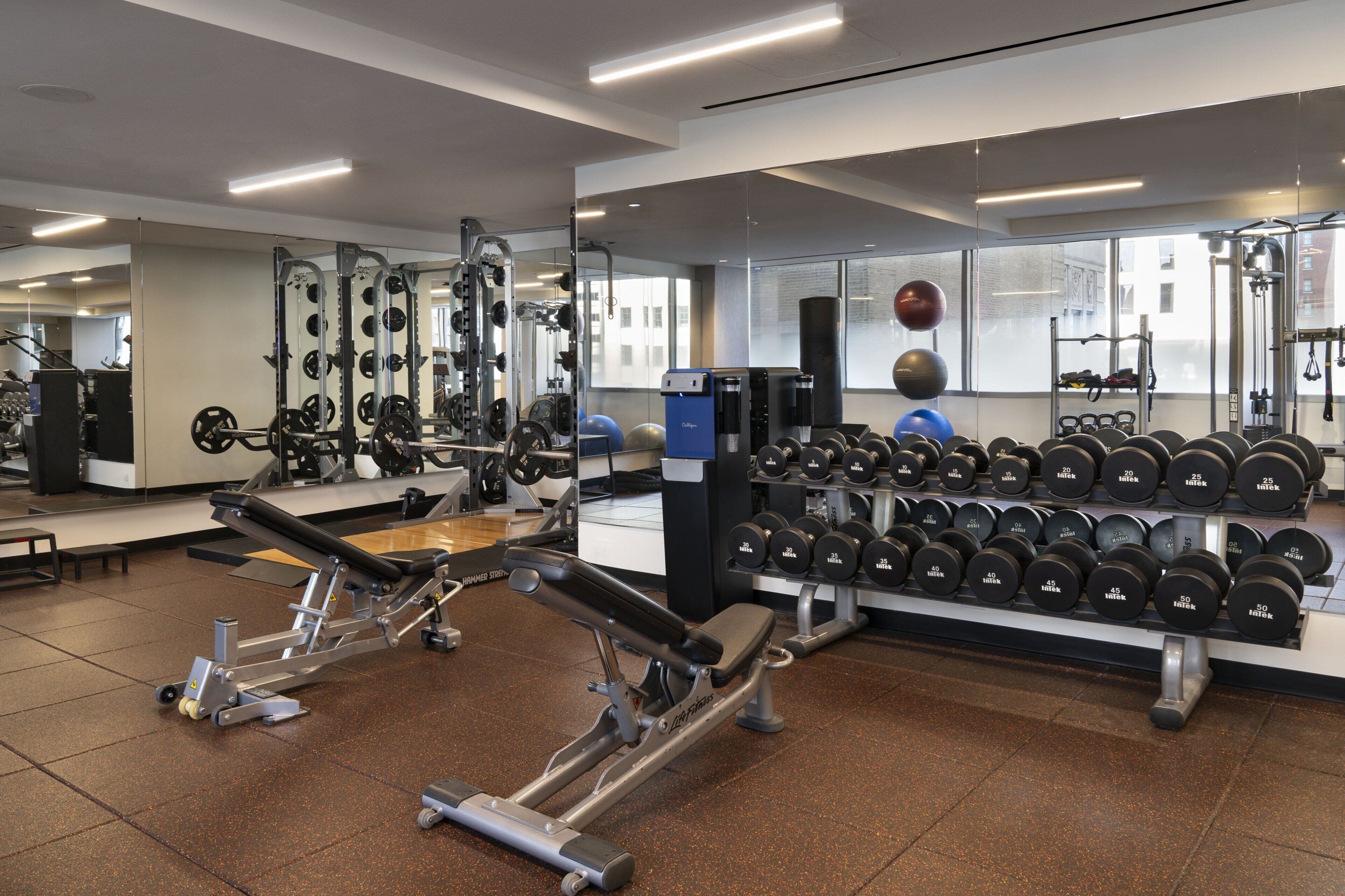 A gym with weightlifting equipment, dumbbells, and exercise balls.