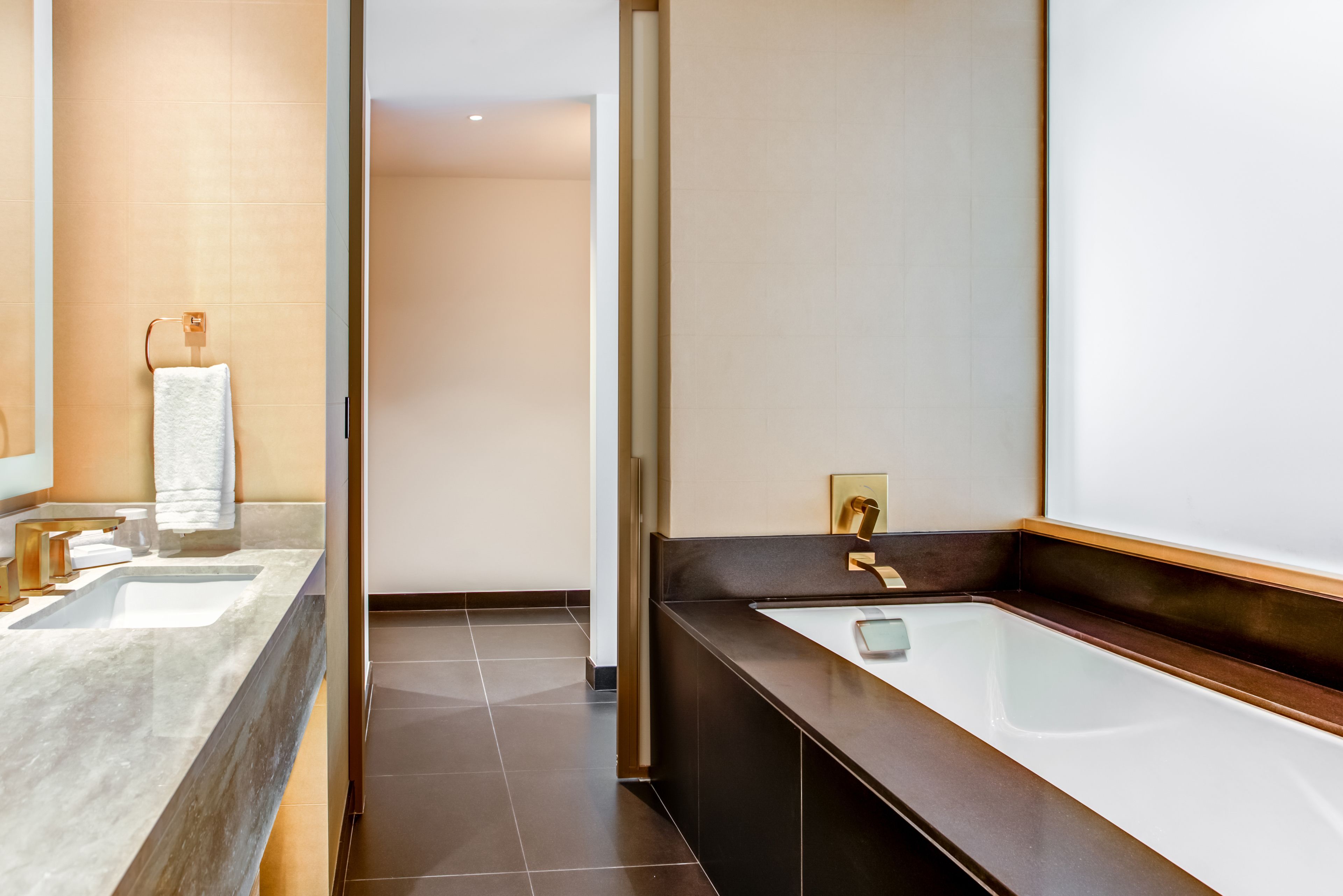 A modern bathroom with two sinks, a bathtub, and a large mirror.