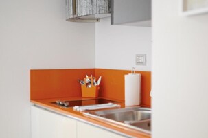 A kitchen with a stainless steel sink, an orange countertop, and a white cabinet above the sink.