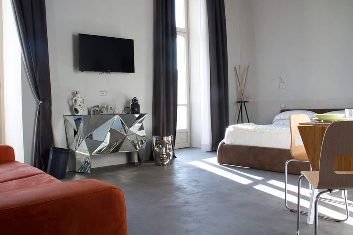 Une chambre d’hôtel moderne équipée d’un lit, d’un bureau, d’une télévision et d’un miroir.