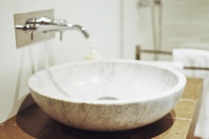 Un bagno con lavabo in marmo, rubinetto cromato e porta asciugamani.