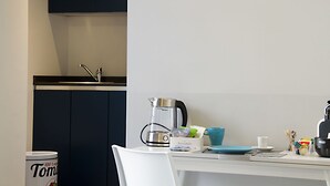A kitchen with a sink, a kettle, a coffee maker, and a box of biscotti. - Piazza Castello Suite (Turin)
