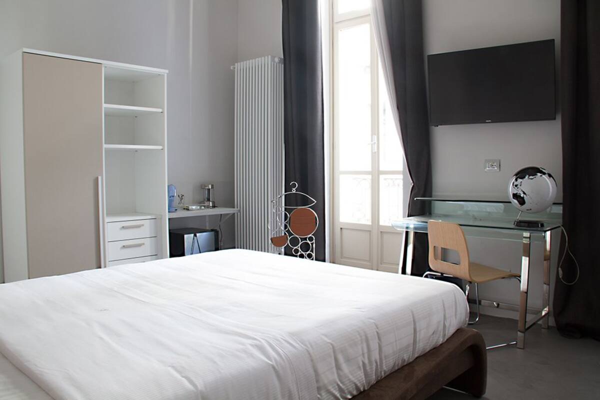 Une chambre à coucher comprenant un lit, un bureau, une chaise, une armoire et un téléviseur.