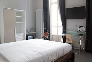 Una camera da letto con un letto, una scrivania, una sedia, un armadio e una TV.