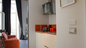 A modern kitchen with white cabinets, an orange countertop, and a black range hood. - Piazza Castello Suite (Turin)