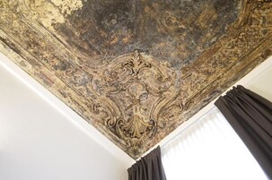 A ceiling with intricate carvings and a window with curtains.