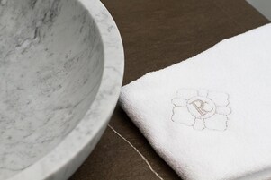 Un cuenco de mármol y una toalla blanca con un monograma.