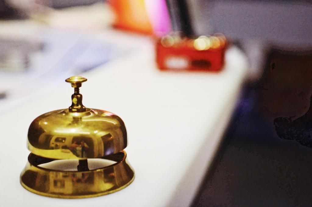 Une cloche en métal posée sur une table, peut-être dans un hôtel.